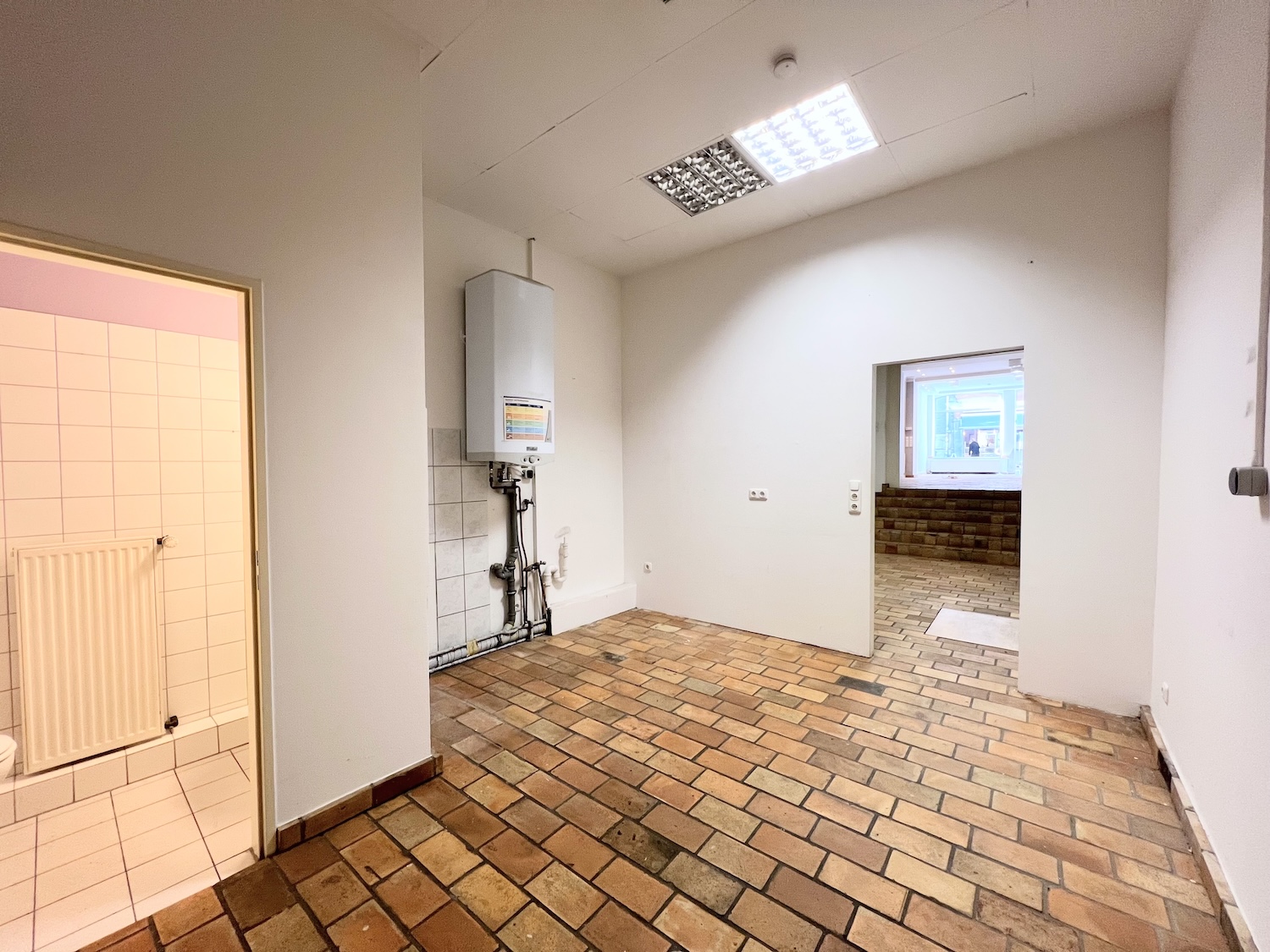 Das Ladenlokal in der Ponnstraße Ansicht Lagerraum mit Blick auf Gäste WC und Etagenheizung, sowie Blick zur Treppe