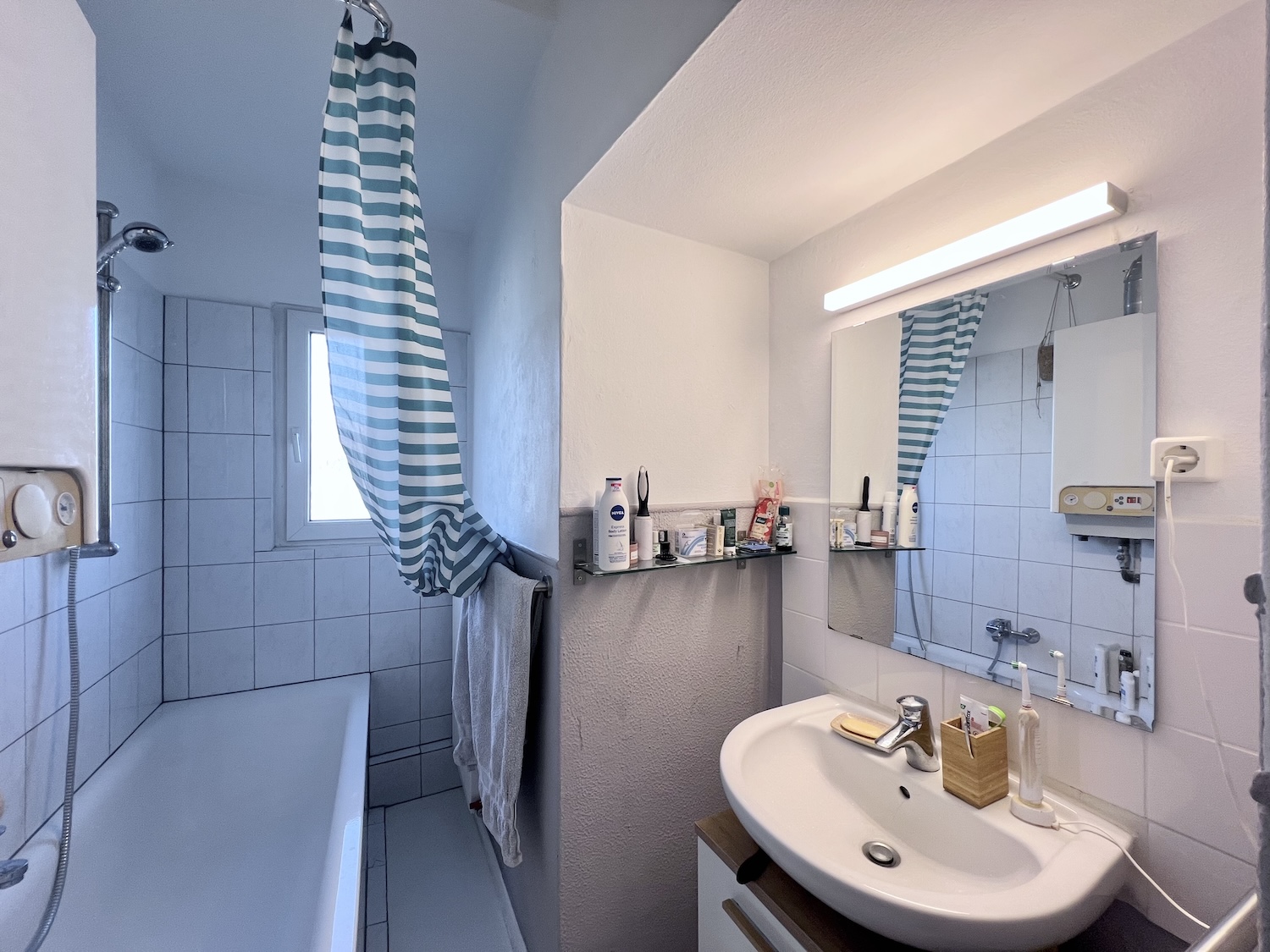 Ansicht Nummer zwei: Badezimmer mit Waschbecken und Badewanne um die Ecke, sowieso Tageslichtfenster