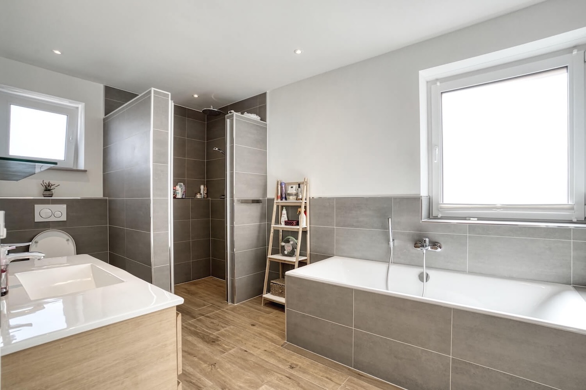 Badezimmer mit Fenster und Badewanne und Dusche