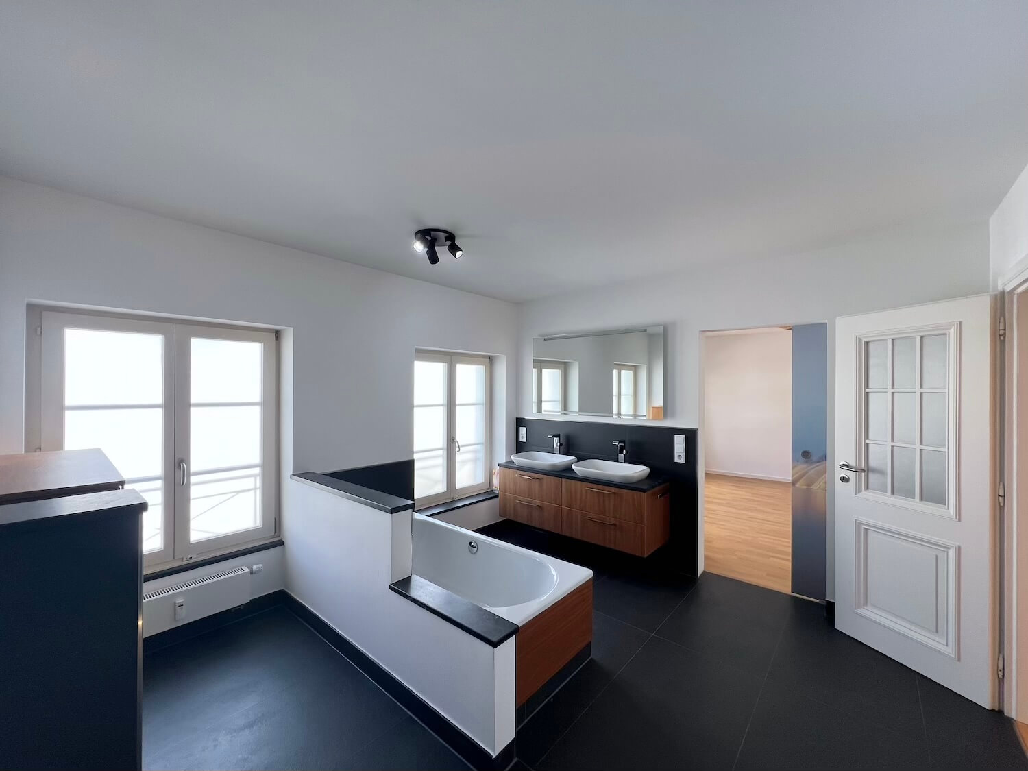 Badezimmer mit Blick auf Wanne und Waschbecken und Zugang zum Schklafzimmer